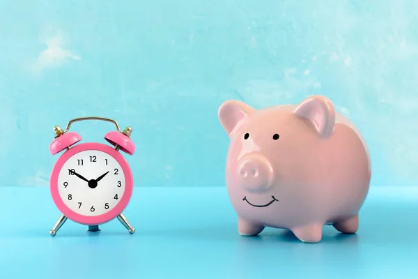 A pink pig piggy bank on a blue background. Nearby is a small pink fridge. — Stock Photo, Image