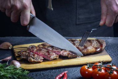 Bir şef taze hazırlanmış bifteği parçalara ayırır. Et orta pişmiş. Lezzetli restoran yemeği