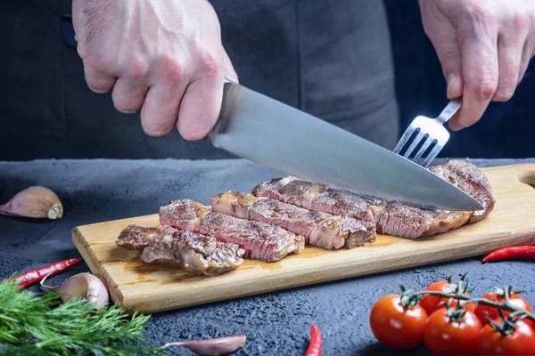 Chef cuts beef steak. Tasty meat of medium roast