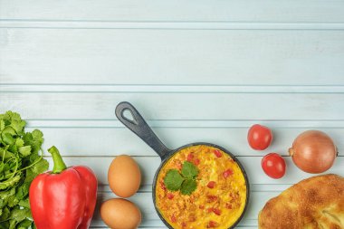 Flatlay mavi arka planda. Domatesli omlet, soğan ve biber, Menemen. Sağlıklı kahvaltı. Fotoğraf alanı kopyala