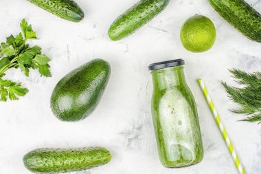 Hafif bir arka planda bir şişe salatalık püresi. Limon ve avokadoyla taze sıkılmış salatalık suyu. Düz konum, malzemeler