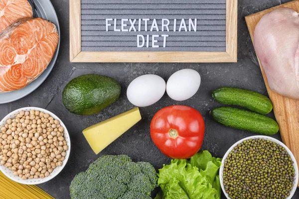 Los alimentos saludables para la dieta, el salmón, las verduras, los huevos y el pollo se exponen sobre un fondo negro. Letras dieta flexitariana Fotos de stock