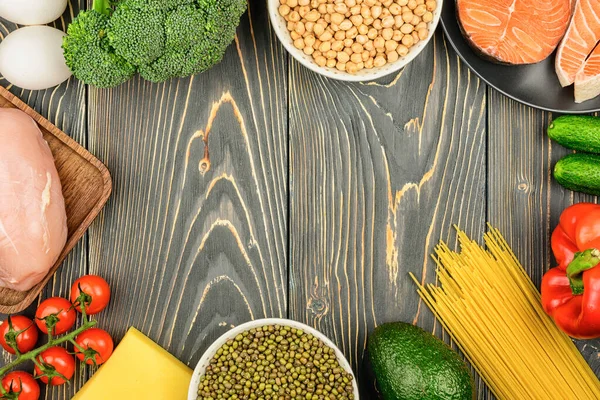 Copia el espacio en el centro de un fondo de madera. Los alimentos saludables para la dieta se establecen alrededor. Salmón, verduras, huevos y pollo. Dietas flexibles Fotos de stock libres de derechos