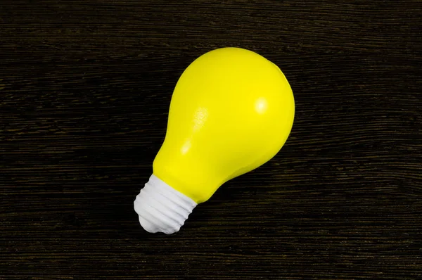 Ampoule jaune comme symbole d'idée sur un fond sombre — Photo