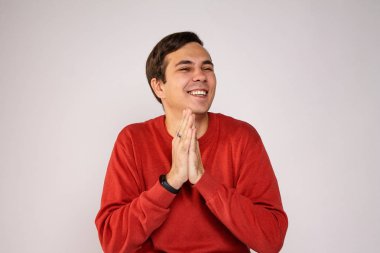 Kırmızı kazaklı genç bir adam gülüyor. Açık arkaplanda portre