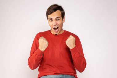 Kırmızı kazaklı genç bir adam mutlu bir şekilde bağırıyor.