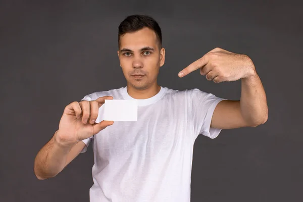 Молодий чоловік у білій футболці тримає візитку — стокове фото