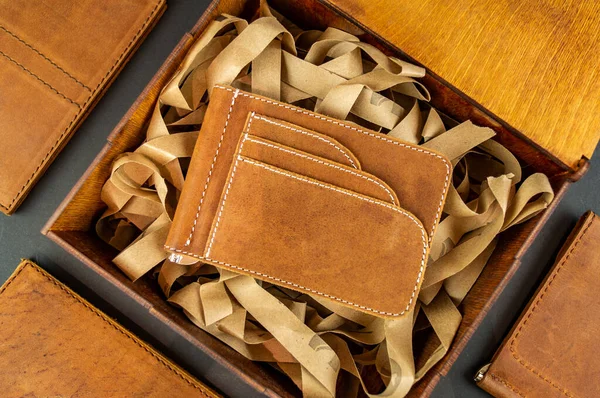 Brieftasche aus echtem Leder auf dem Tisch beim Verpacken eines Geschenks auf braunem Hintergrund — Stockfoto