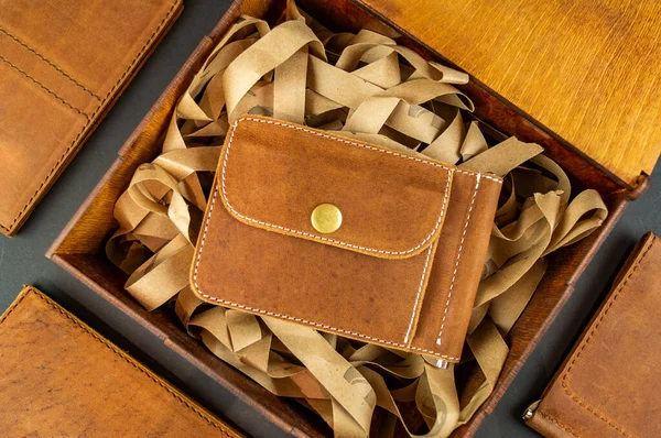 Wallet made of genuine leather on the table in the process of packing a gift on a brown background — ストック写真