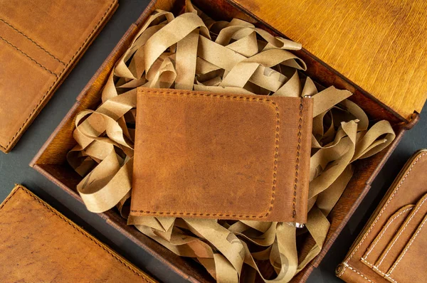 Brieftasche aus echtem Leder auf dem Tisch beim Verpacken eines Geschenks auf braunem Hintergrund — Stockfoto