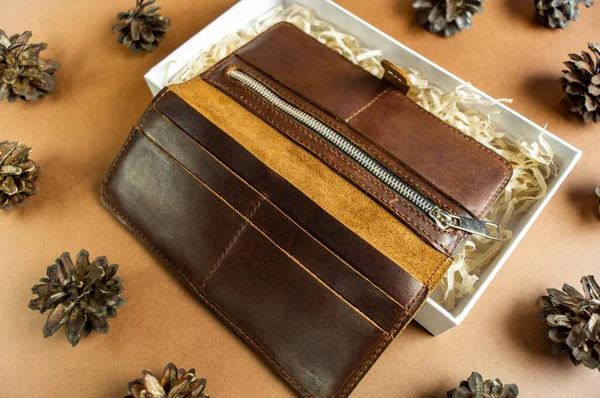 wallet made of genuine leather on the table in the process of packing a gift on a brown background