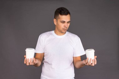 Beyaz tişörtlü adam iki çeşit kahve arasında seçim yapmaya çalışıyor..