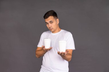 Beyaz tişörtlü adam iki çeşit kahve arasında seçim yapmaya çalışıyor..