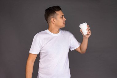 Beyaz tişörtlü bir adam sabahları aç gözlülükle kahve içer..