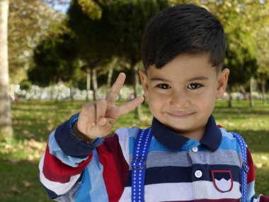 Gülümseyen genç küçük çocuk bir zafer işareti verir