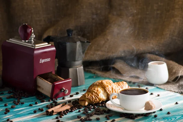 Φλιτζάνι ζεστό καφέ και κρουασάν σε φόντο ξύλινη — Φωτογραφία Αρχείου