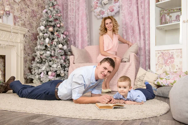 Szczęśliwych rodziców z toddler chłopiec czytać książki w Boże Narodzenie — Zdjęcie stockowe