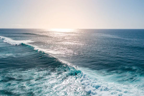 aerial view of a surfer riding a surf at sunset, Surfer ride on waves in ocean sunset, top view