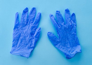 Mavi arka planda mavi eldivenlerin üst görüntüsü. Tıp çalışanları için tıbbi cerrahi koruma kiti, doktorlar. Sağlık hizmetleri kavramı