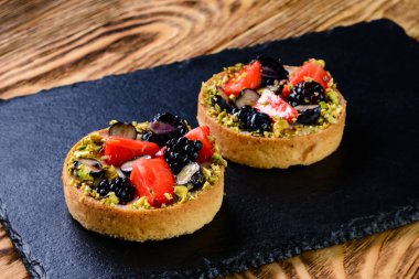 Lezzetli Mini tatlı tart tatlı pastalar, kırsal ahşap masa tartı ve taze böğürtlen.