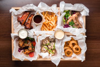 Koyu ahşap masada yiyecek ve atıştırmalıklar var. İtalyan yemek masası, üst manzara.