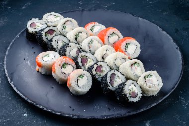 Suşi, geleneksel Japon yemekleri olan siyah bir masaya kurulur. Suşi, karanlık bir arka planda yuvarlanır. Üst görünüm