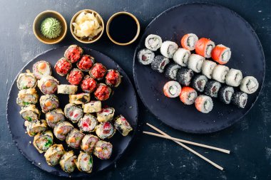 Suşi, geleneksel Japon yemekleri olan siyah bir masaya kurulur. Suşi, karanlık bir arka planda yuvarlanır. Üst görünüm