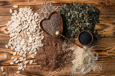 Sağlıklı tohum koleksiyonu Tahta arka planda Chia tohumları, balkabağı tohumları ve susam tohumları düz yatıyordu