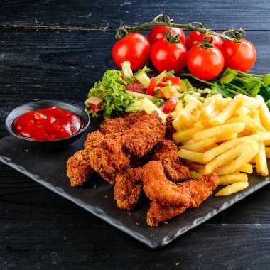Kızarmış tavuk, nugget ve patates kızartması, tavuk nugget seti, salata ve tahta masada patates kızartması. Gıda sorunu.