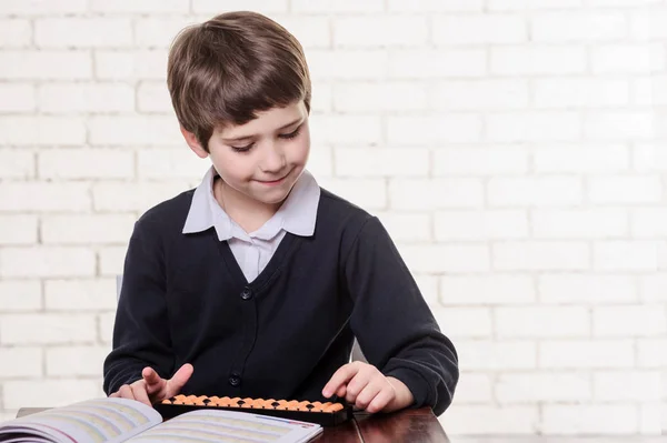 Portrait of primary school boy using abacus mental arithmetic. — Stock Photo, Image