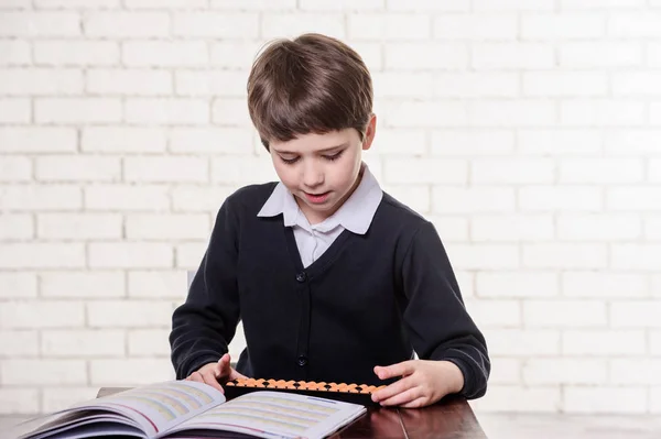 Portrait of primary school boy using abacus mental arithmetic. — Stock Photo, Image