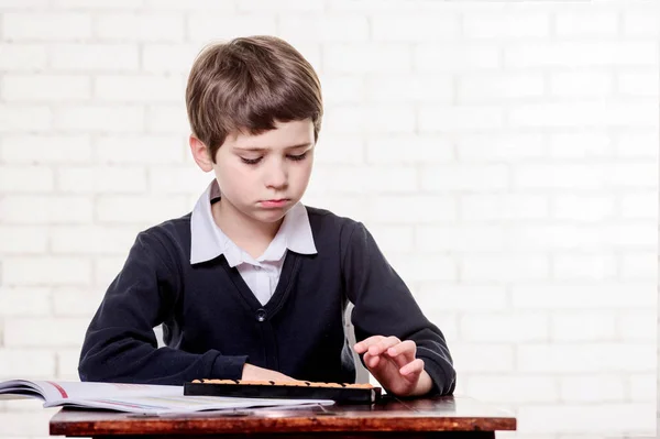 Portrait of primary school boy using abacus mental arithmetic. — Stock Photo, Image