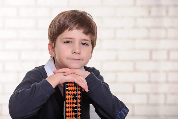 Portret van basisschool jongen met behulp van abacus geestelijke rekenkundig. — Stockfoto