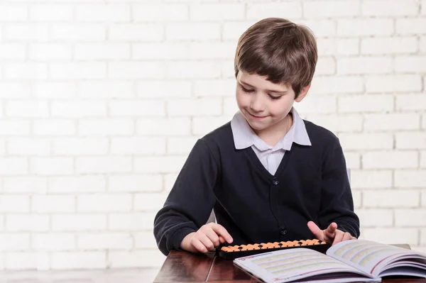 Portrait of primary school boy using abacus mental arithmetic. — Stock Photo, Image