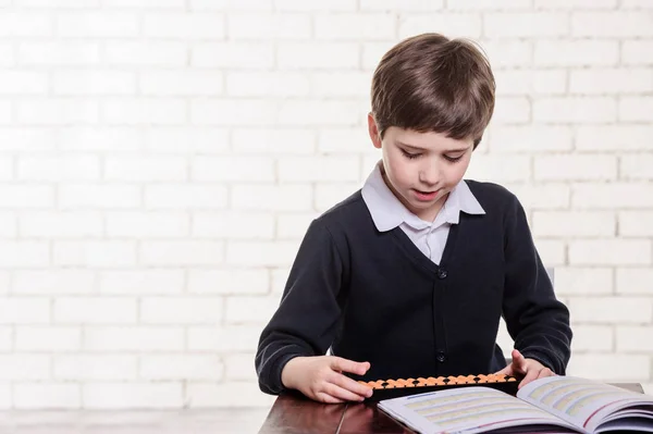 Portrait of primary school boy using abacus mental arithmetic. — Stock Photo, Image