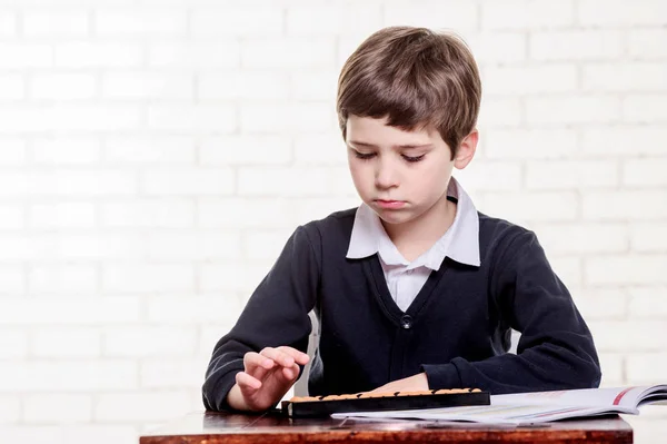 Portrait of primary school boy using abacus mental arithmetic. — Stock Photo, Image