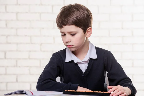 Portrait of primary school boy using abacus mental arithmetic. — Stock Photo, Image