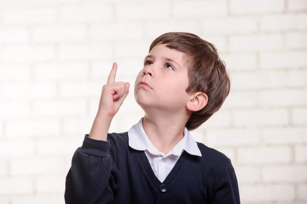 Happy primary school boy points up with his finger. — Stock Photo, Image