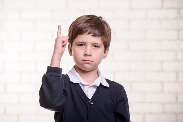 Happy primary school boy points up with his finger. — Stock Photo, Image