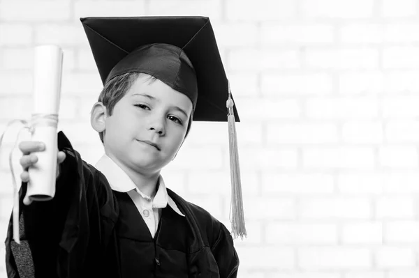 Niño de escuela primaria en copa y vestido posando con diploma — Foto de Stock