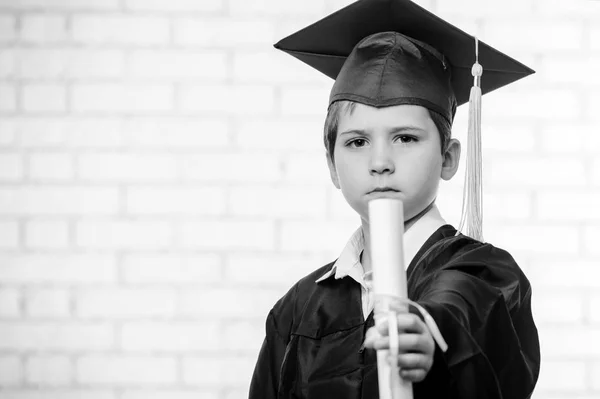 Primary school boy in cup and gown posing with diploma — Stock Photo, Image