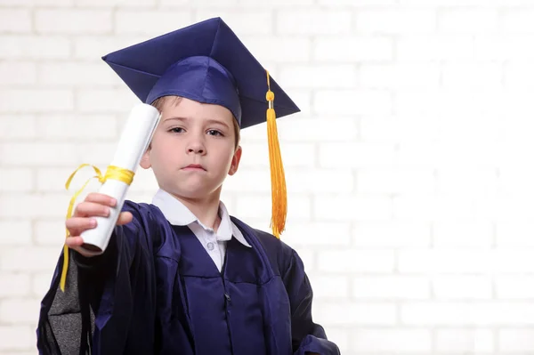 Niño de escuela primaria en copa y vestido posando con diploma —  Fotos de Stock