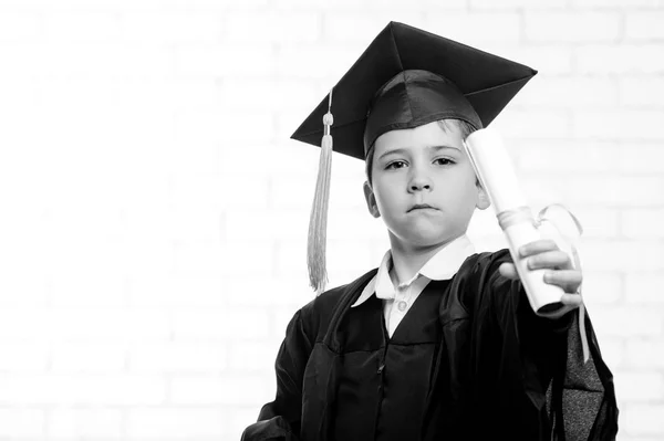 Grundskola pojke i cup och klänning poserar med sin diplom svart och vitt — Stockfoto