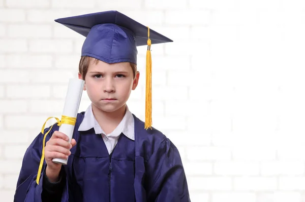 Menino da escola primária em copo e vestido posando com seu diploma — Fotografia de Stock