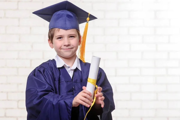 Niño de escuela primaria en copa y vestido posando con su dedo — Foto de Stock