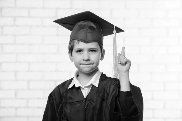 Niño de la escuela primaria en copa y vestido posando con el dedo en blanco y negro —  Fotos de Stock