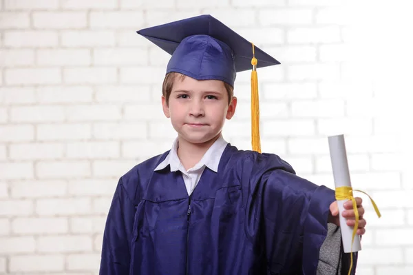 Základní škola chlapec v poháru a šaty pózuje s diplomem. — Stock fotografie