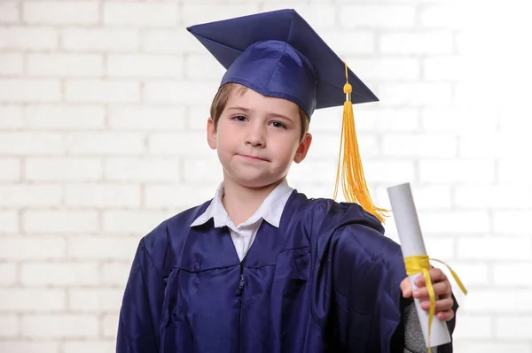 Garçon de l'école primaire en coupe et robe posant avec diplôme . — Photo