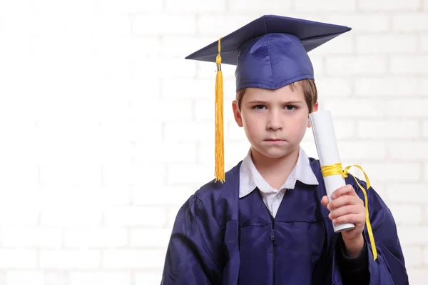 Menino da escola primária em copo e vestido posando com diploma . — Fotografia de Stock