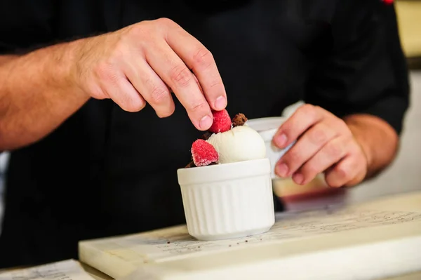 Cheef's hands decorating ise cream with berry. — Stock Photo, Image